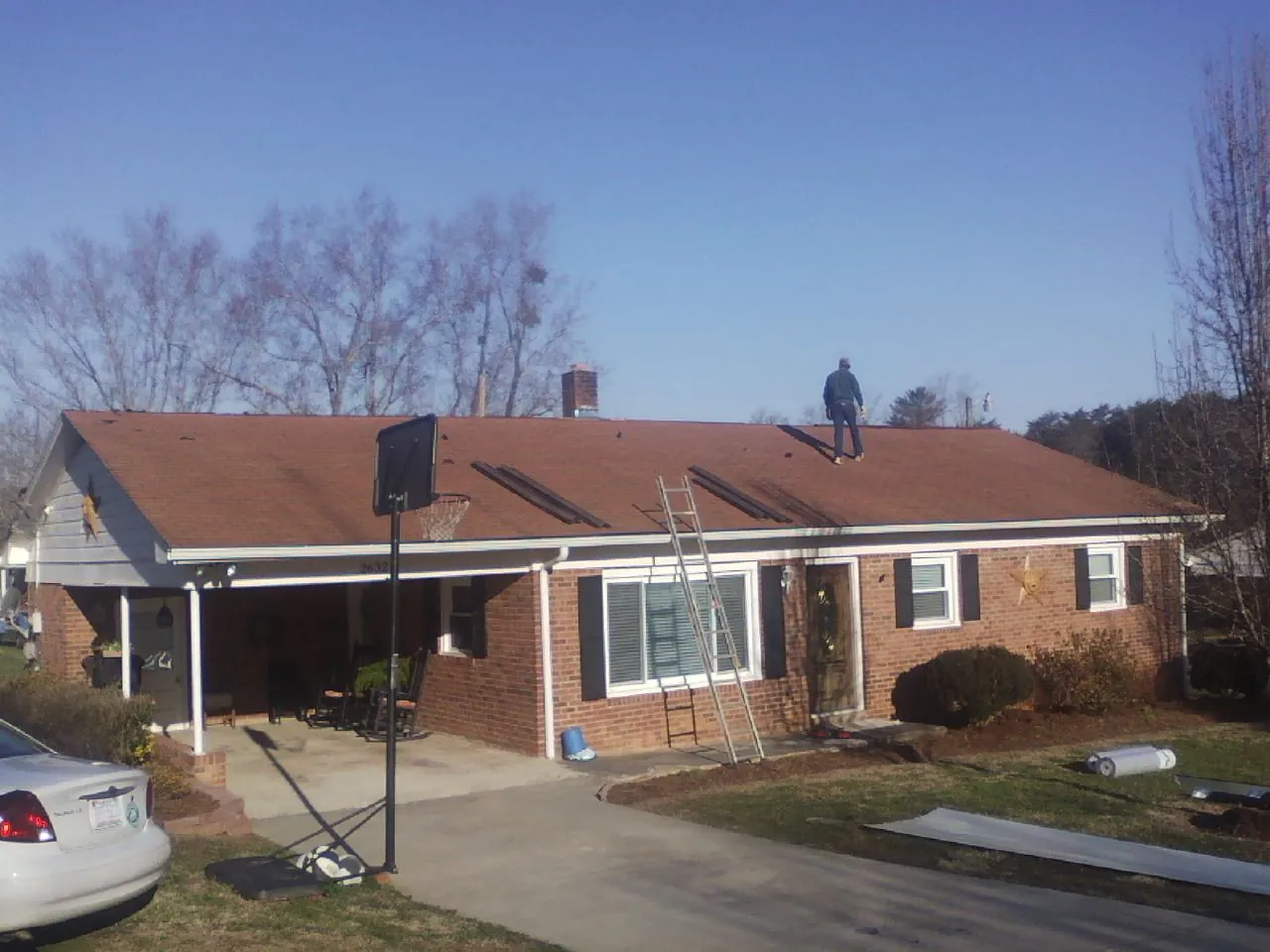 Roofer stripping a shingle roof on a brick ranch before metal panels in Matlock