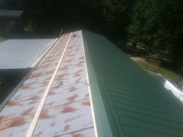 Old rusted panels beside newly installed green metal roofing — Wind Damage Roof Repair by Roofing Brothers in Matlock