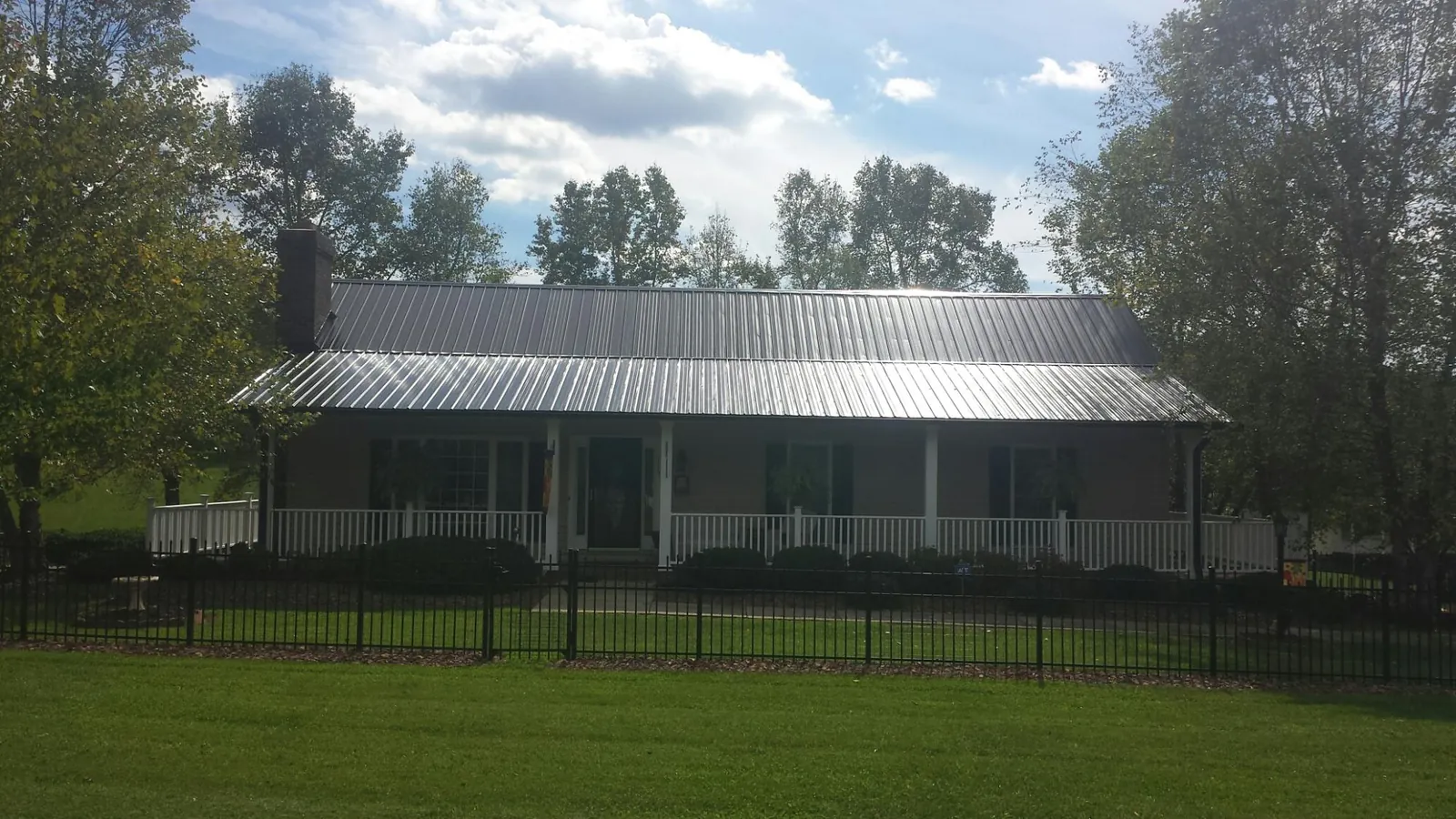 Gray metal roof on a brick ranch with a full width front porch — Gutter Guard Installation work by our crew in Matlock