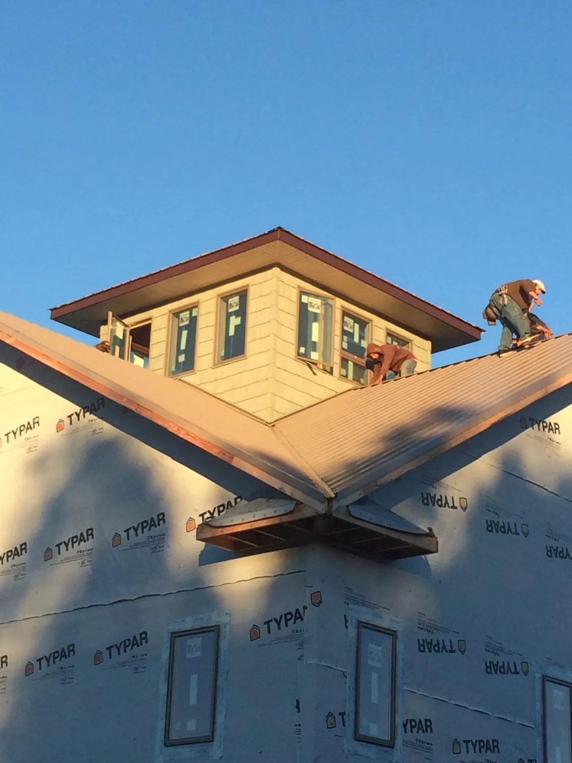Roofers working around a rooftop cupola on a new metal roof at sunset — Roof Waterproofing in Matlock by Roofing Brothers